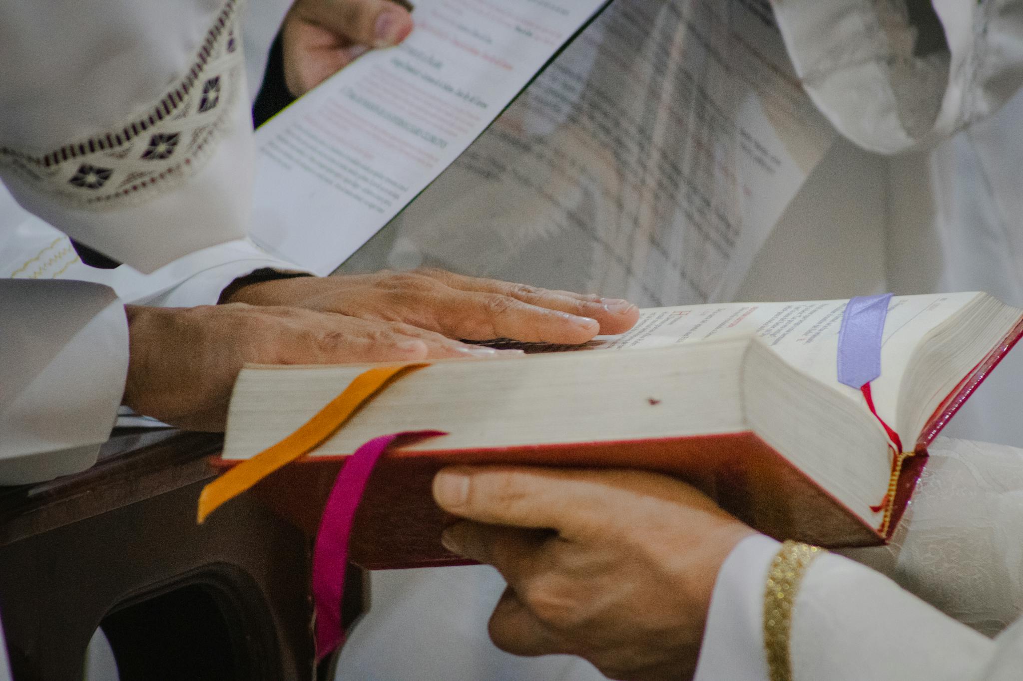 Priest during a sacred ceremony holding a holy book with ribbons. A spiritual moment captured indoors.